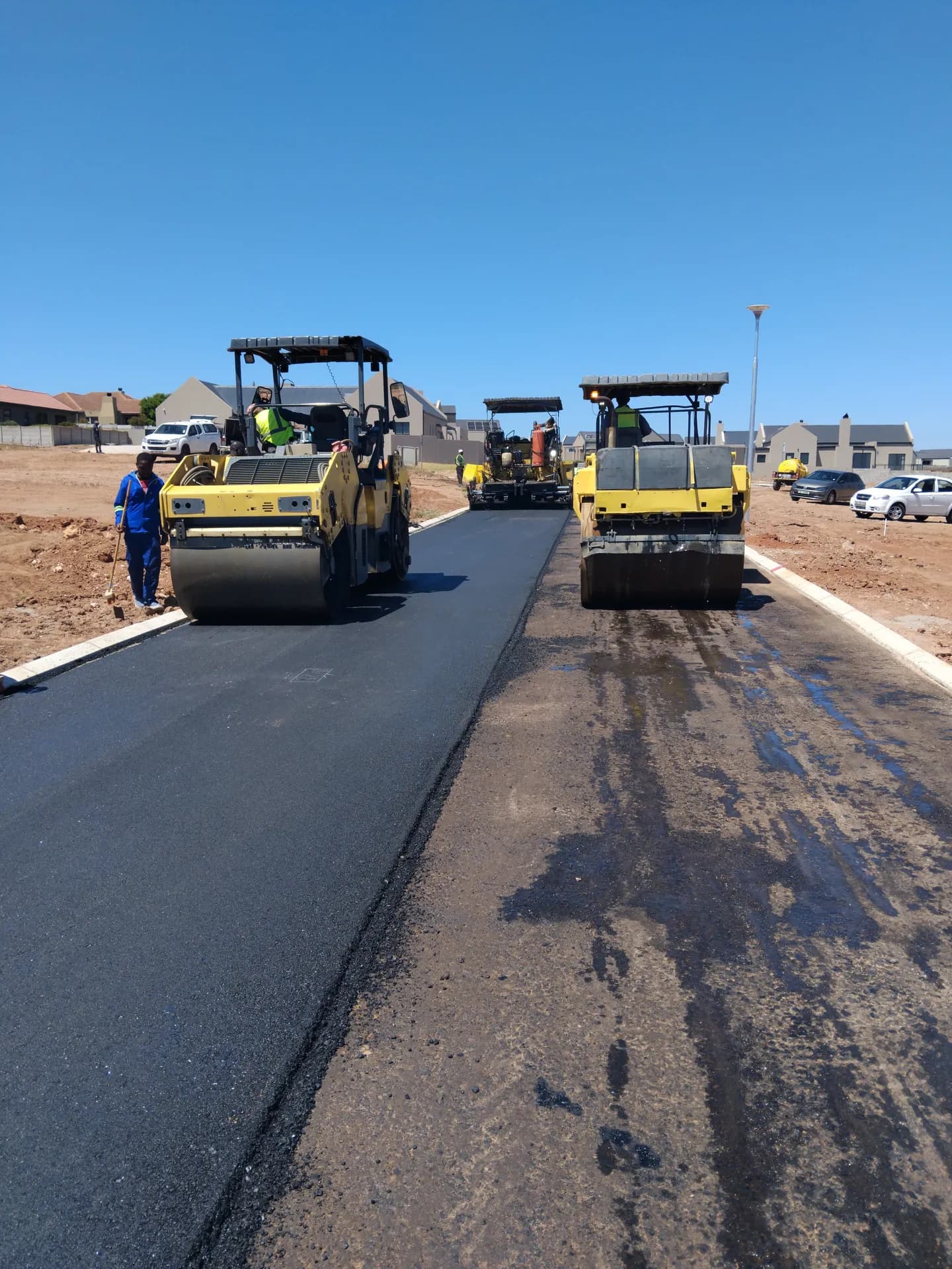 Two rollers compacting fresh asphalt on a new street